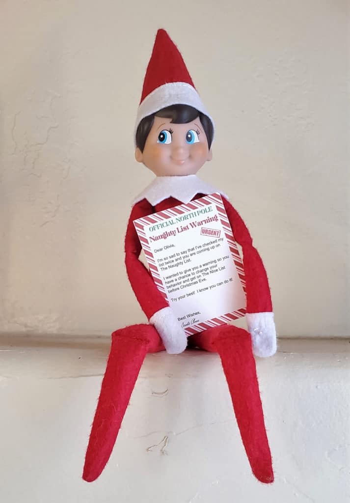 elf on the shelf holding naughty list letter from Santa